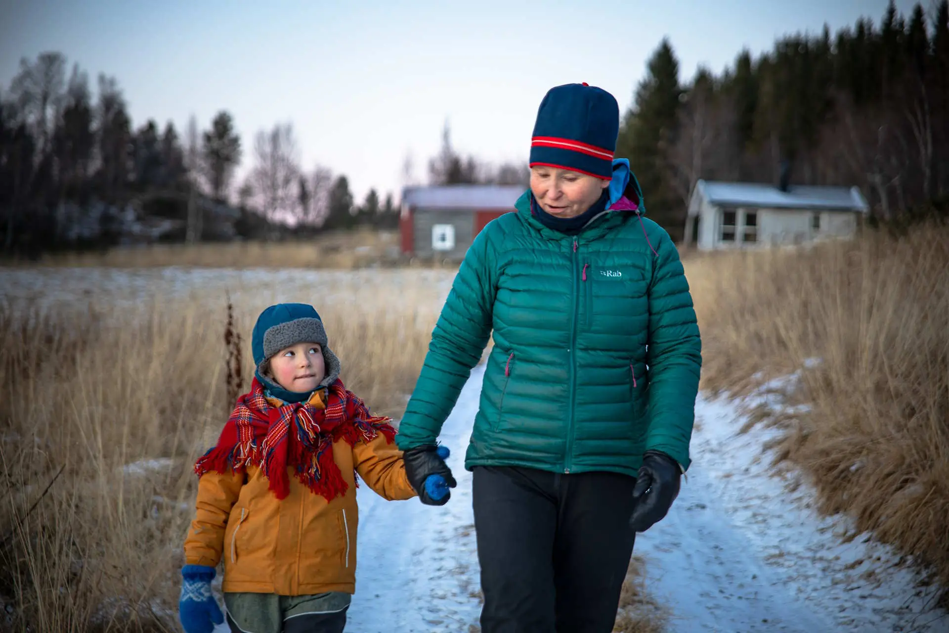 Stillbilde fra "Samiske fortellinger om rett og urett". En dame og et barn går hånd i hånd kledd i vinterklær. Foto.