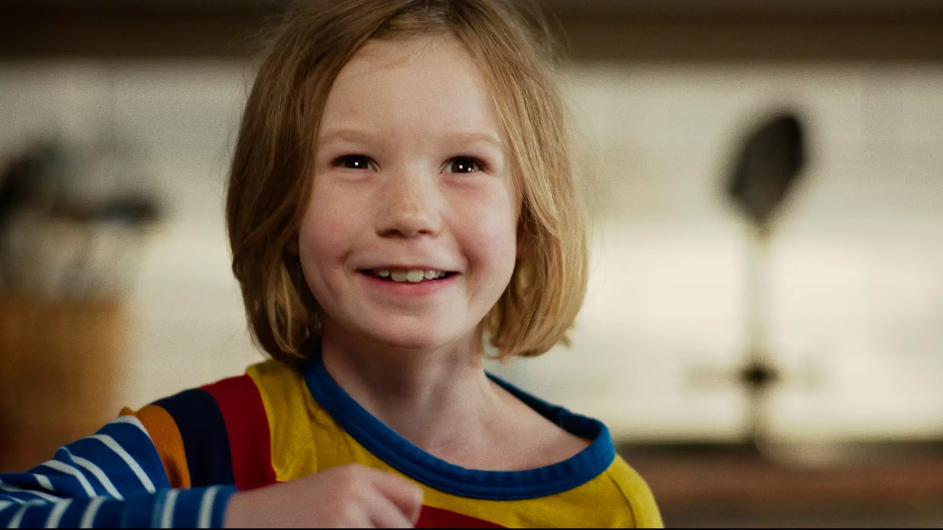 Nærbilde av ei ung jente med rødlig kort hår som smiler.