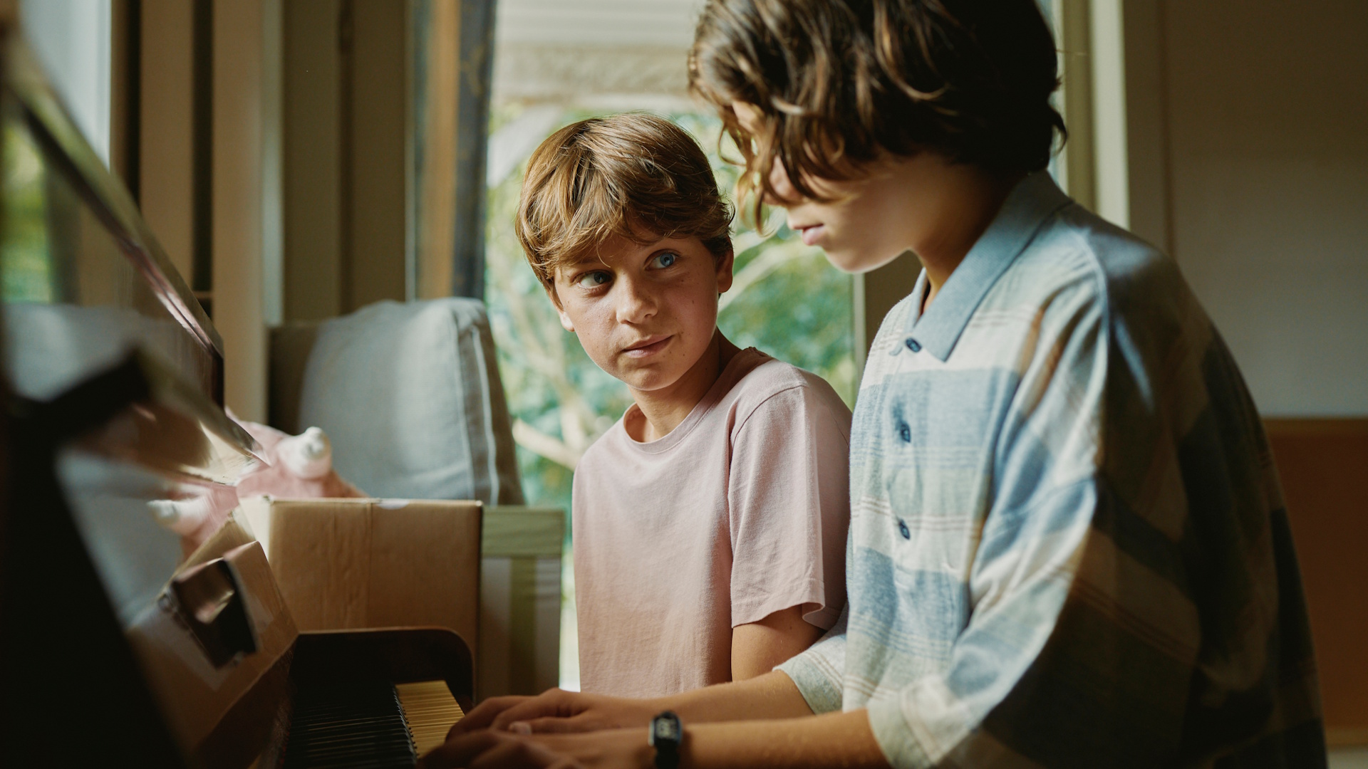 Stillbilde fra "Young Hearts". To gutter spiller piano sammen inne i et lyst rom. Foto