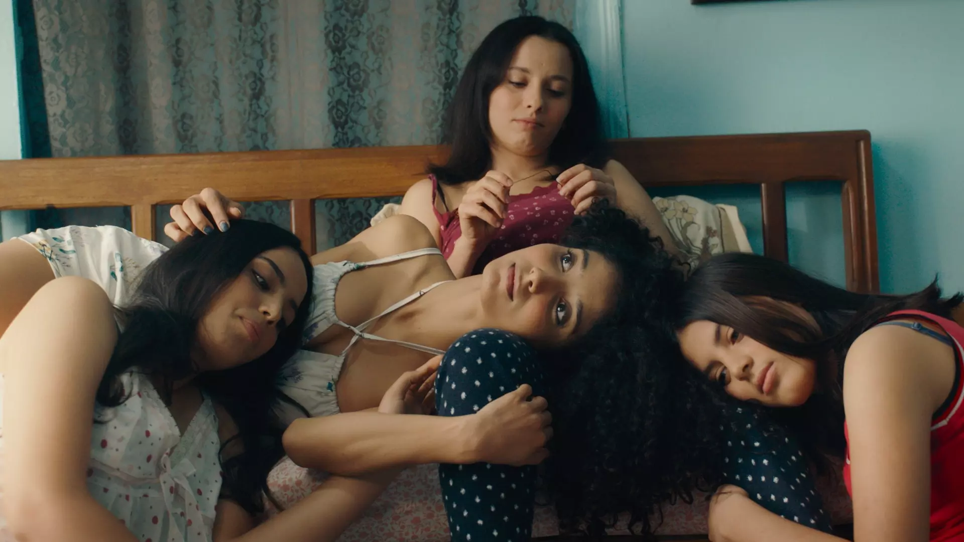Fire unge tunisiske kvinner lener seg over hverandre i en seng. 