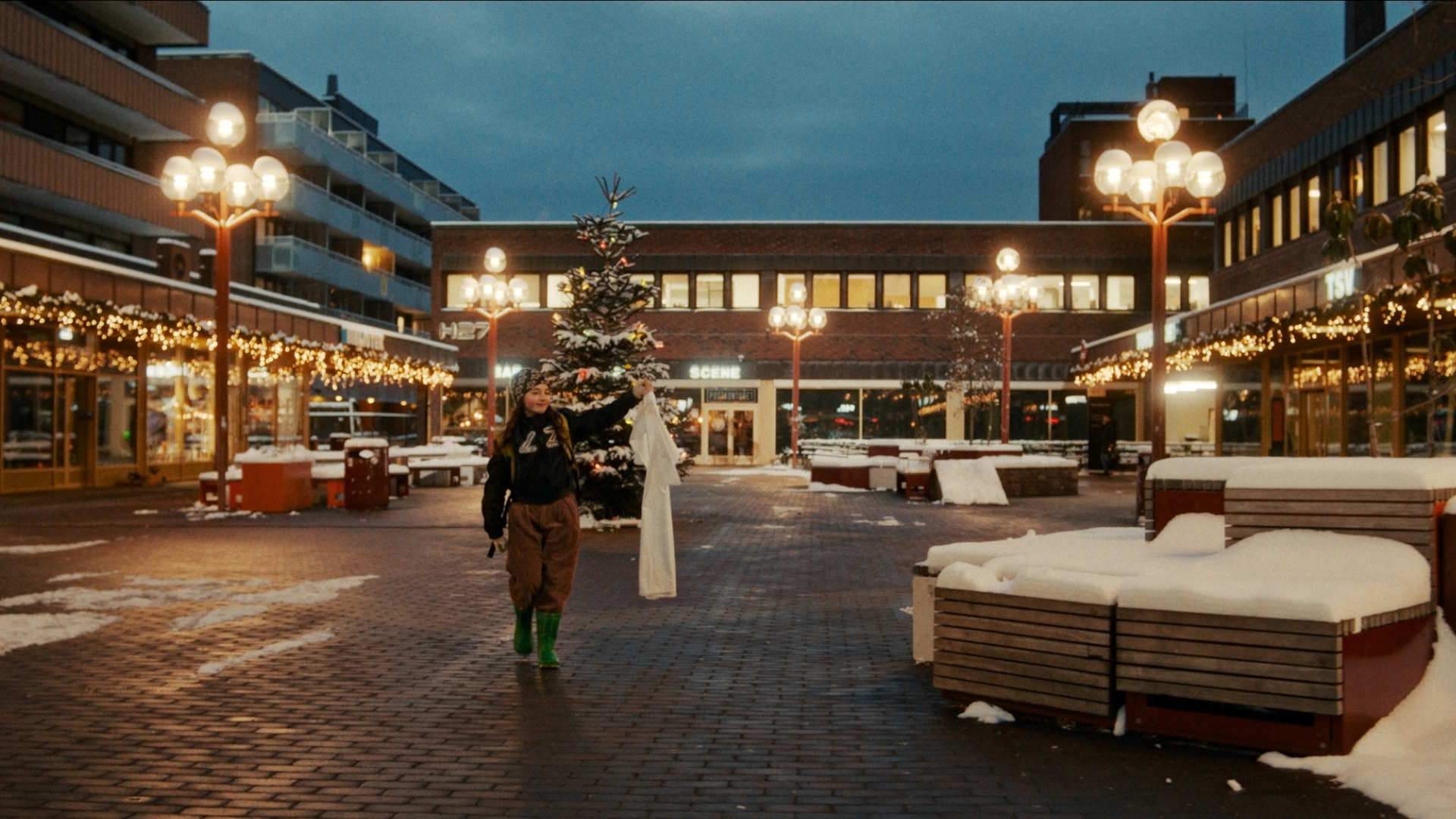 Stillbilde fra "Stargate - en julefortelling". Jente bærer en hvit kjole gjennom Grønland torg. Foto.