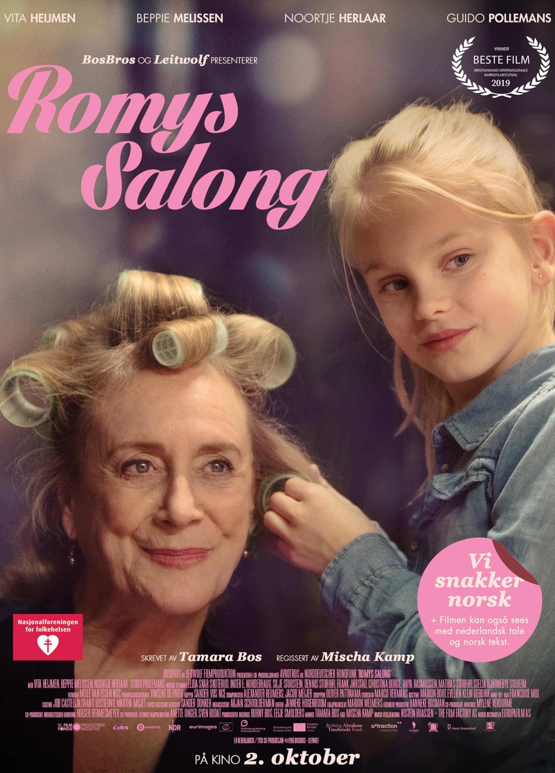 Filmplakat for filmen "Romys salong" hvor en eldre kvinne og en liten jente er sentrale karakterer. Jenta setter hårruller i håret til kvinnen. Filmtittelen står med rosa, pene bokstaver. Foto.