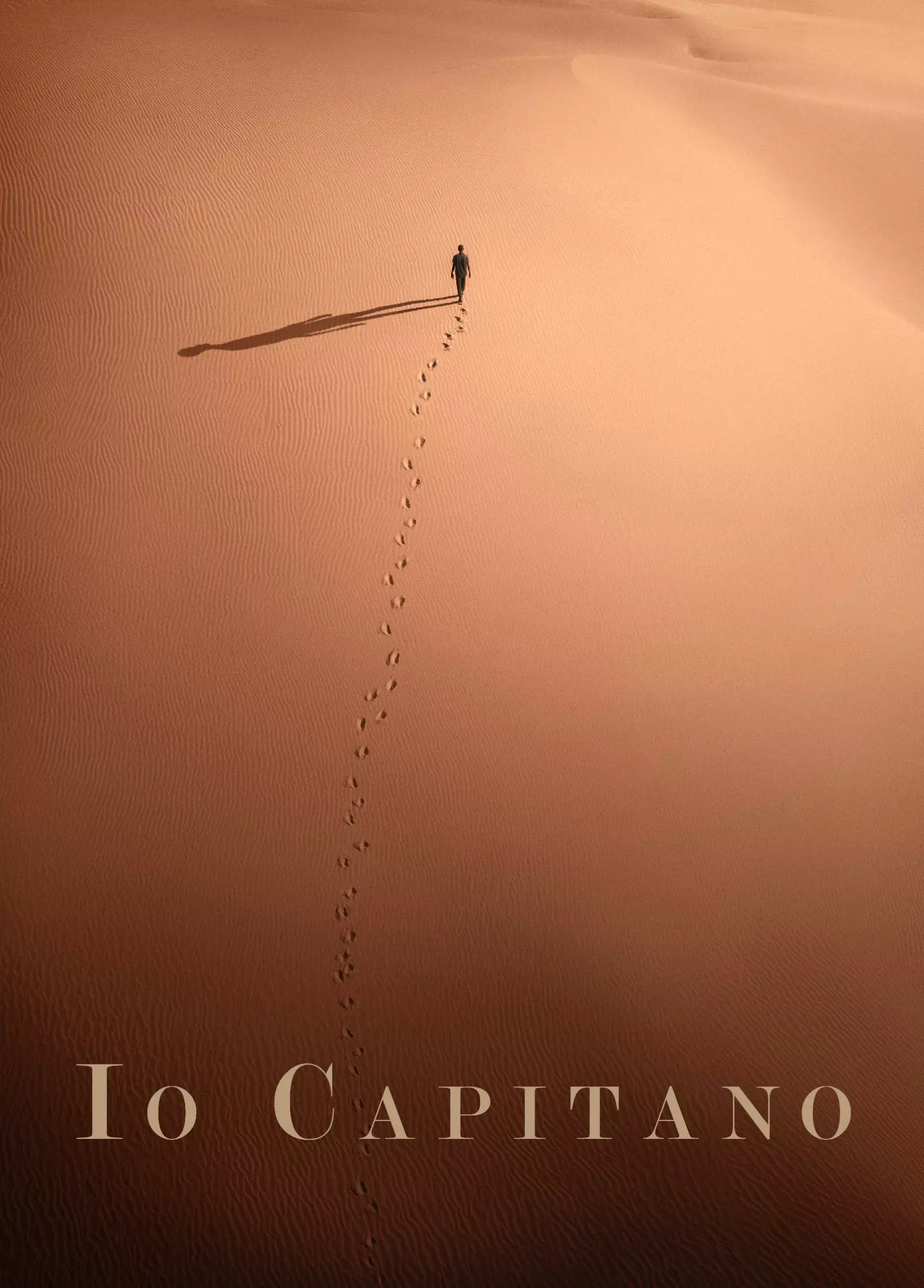 Filmplakat til "Io Capitano". Totalbilde i fugleperspektiv. En person går i ørkenen. Foto.