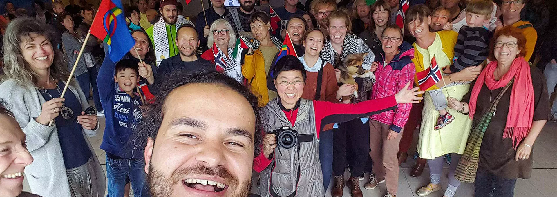 Stillbilde hentet fra filmen "Livet er vakkert". En stor gruppe mennesker som smiler og feirer på en selfie. Foto.