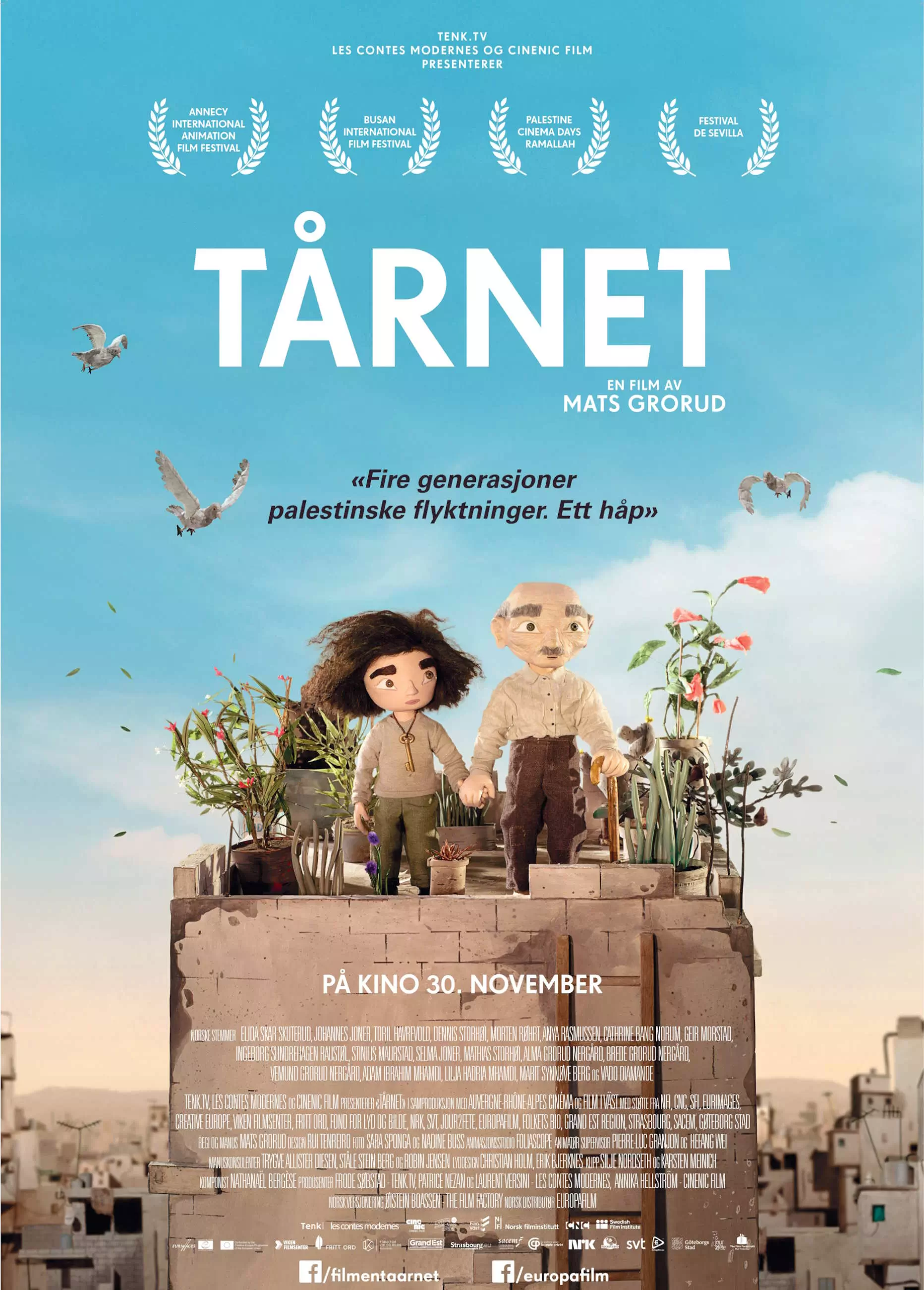 Filmplakat til "Tårnet". To dukkefigurer står på toppen av et murhus. Det er blåhimmel og fugler som flyr. Filmens tittel står skrevet med store hvite bokstaver. Illustrasjon.