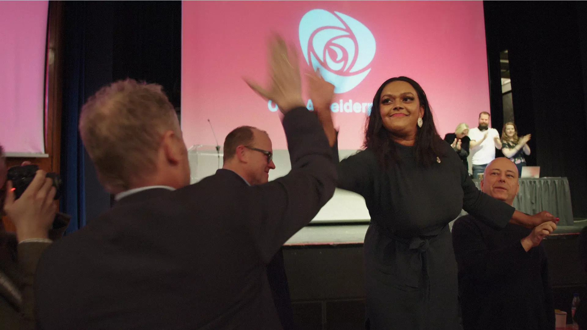 Bilde fra da Kamzy Gunaratnam velges til varaordfører. Hun og en annen politiker gir hverandre high five. De er inne i en konferansesal, og bak dem er en skjerm på en scene med logoen til Arbeiderpartiet. 