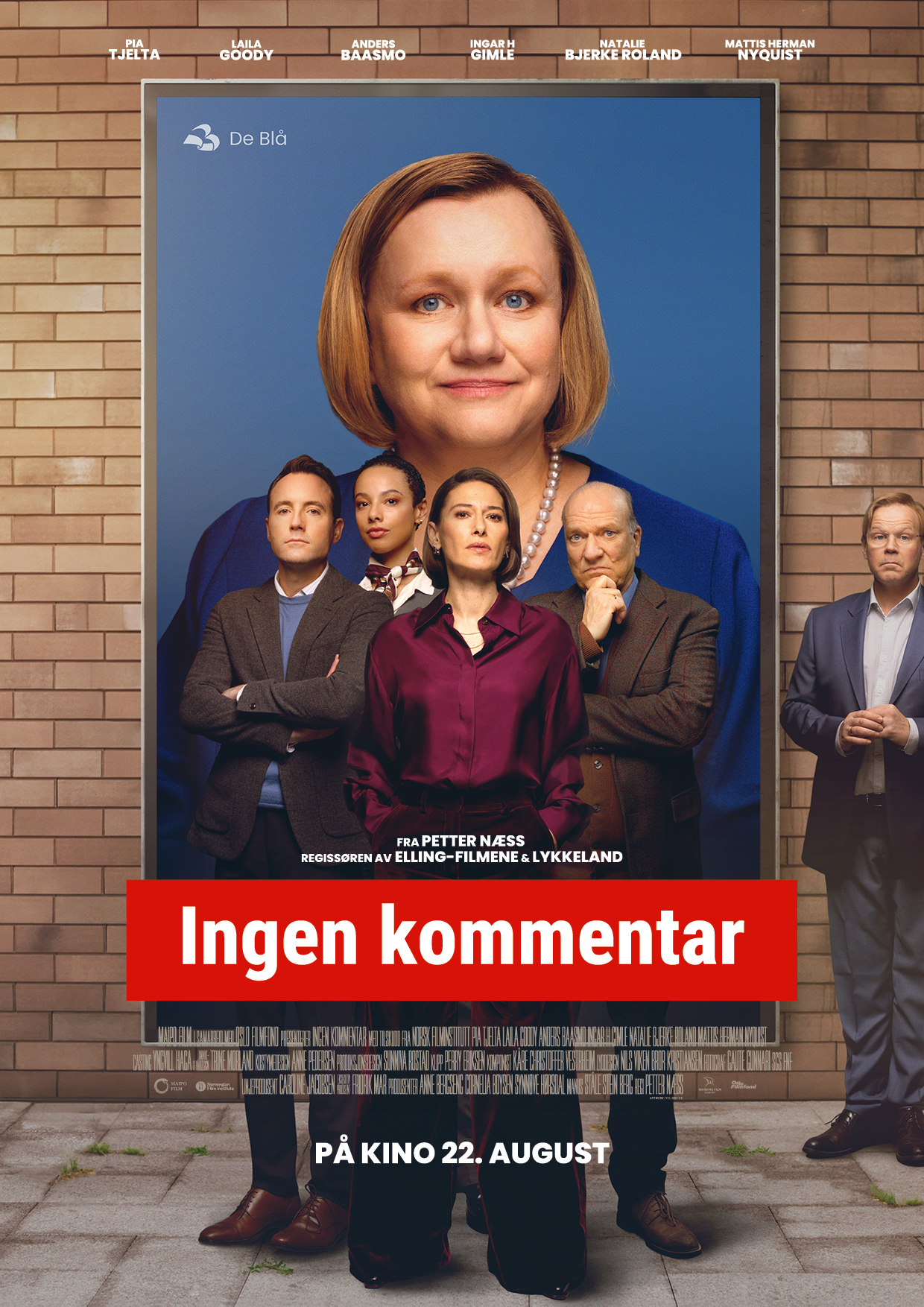 Filmplakat til "Ingen kommentar". Fire alvorlige personer står forran en stor plakat av en dame med blå bakgrunn. Filmtittelen står skrevet med hvit tekst og rød bakgrunn nederst på plakaten. Foto.
