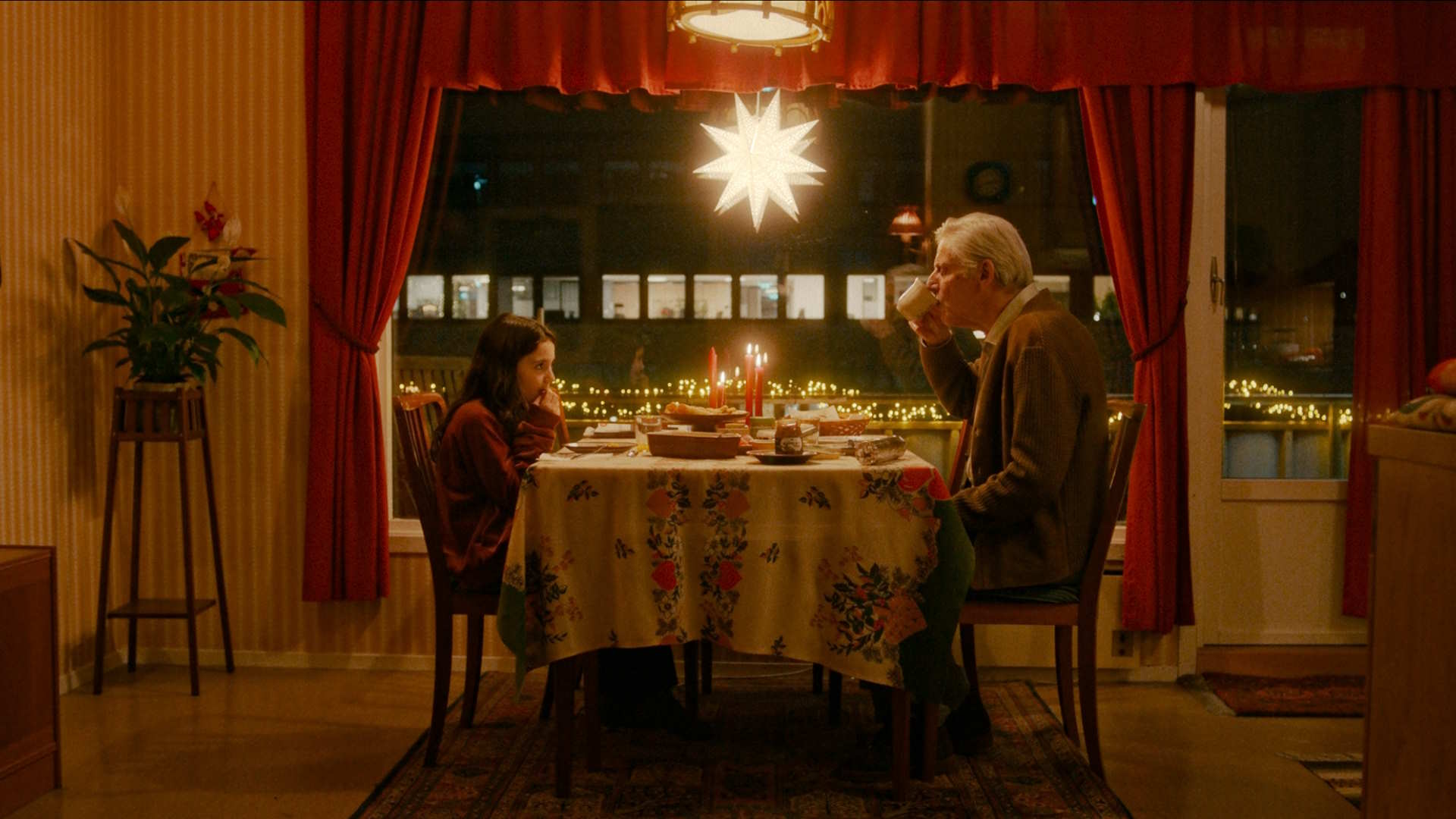 Stillbilde fra "Stargate - en julefortelling". Jente og eldre mann spiser julemat sammen. Foto.